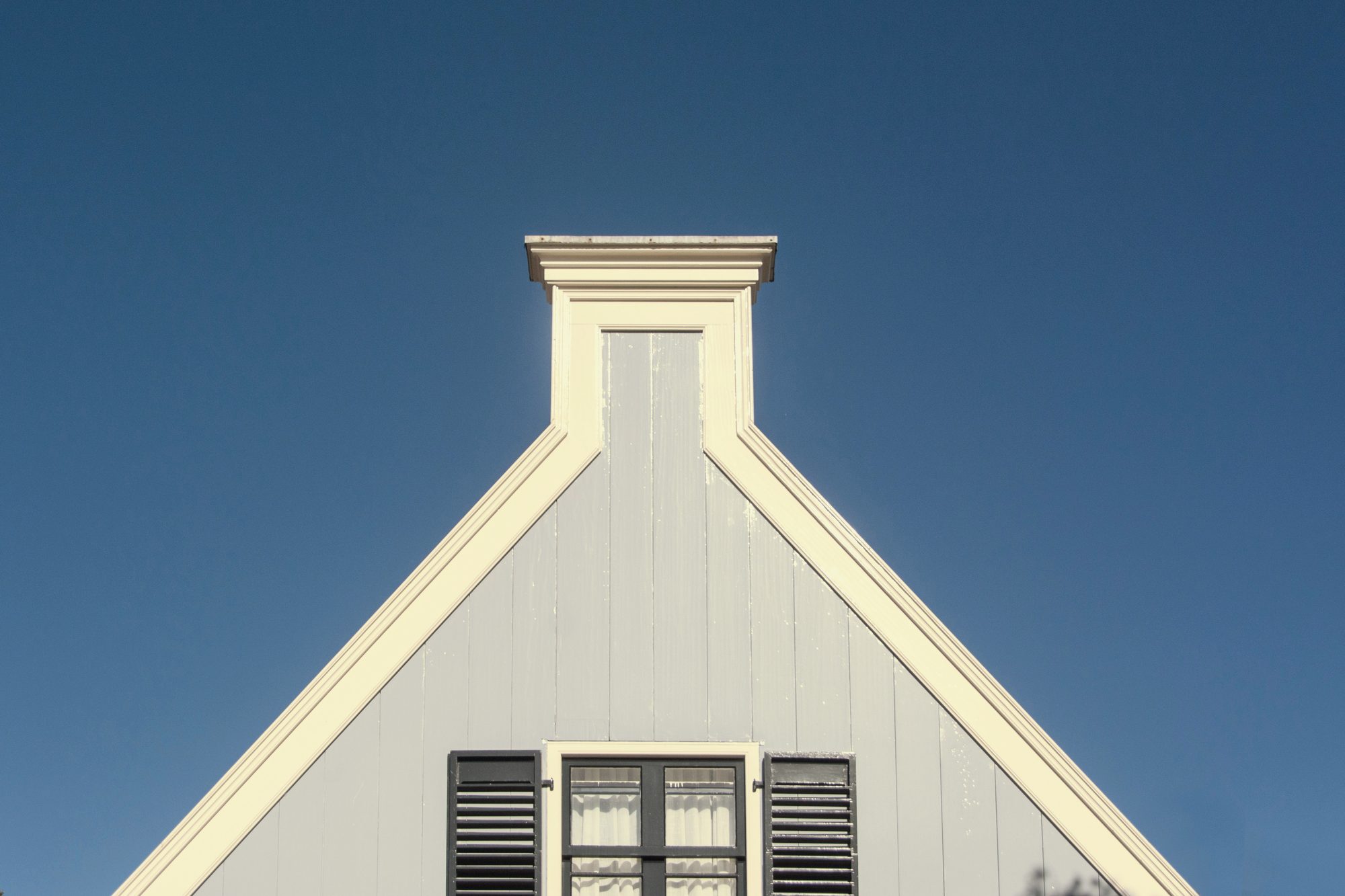The same gable finished: a clean new ridge cap against open blue sky