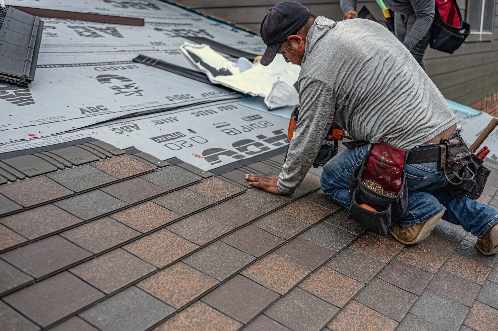 The same slope re-decked and being nailed off in fresh architectural shingle