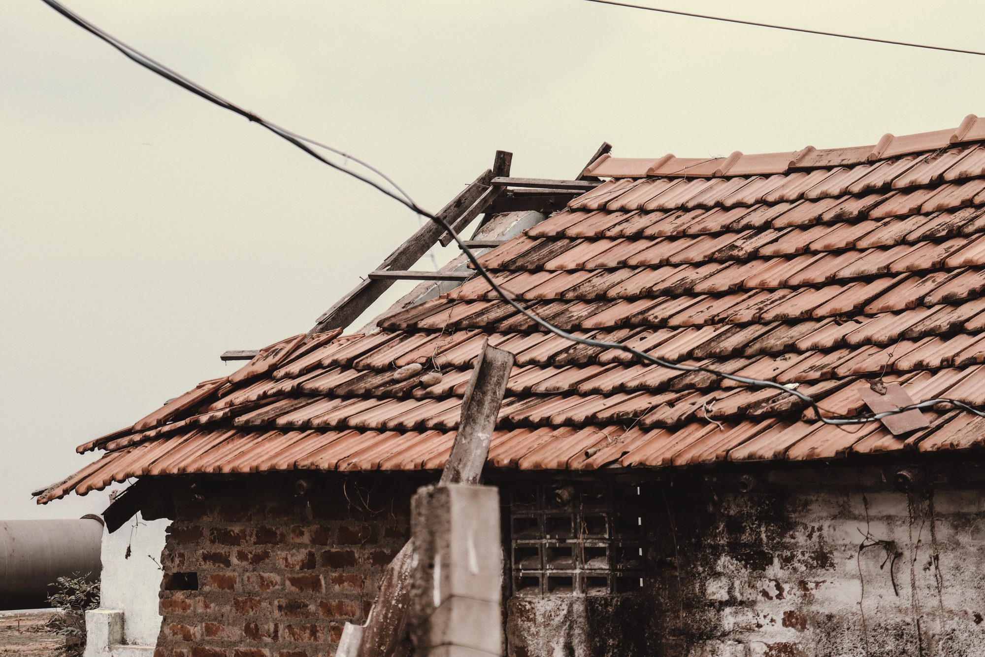 Cracked and slipped tiles on a wind-lifted roof before the tear-off
